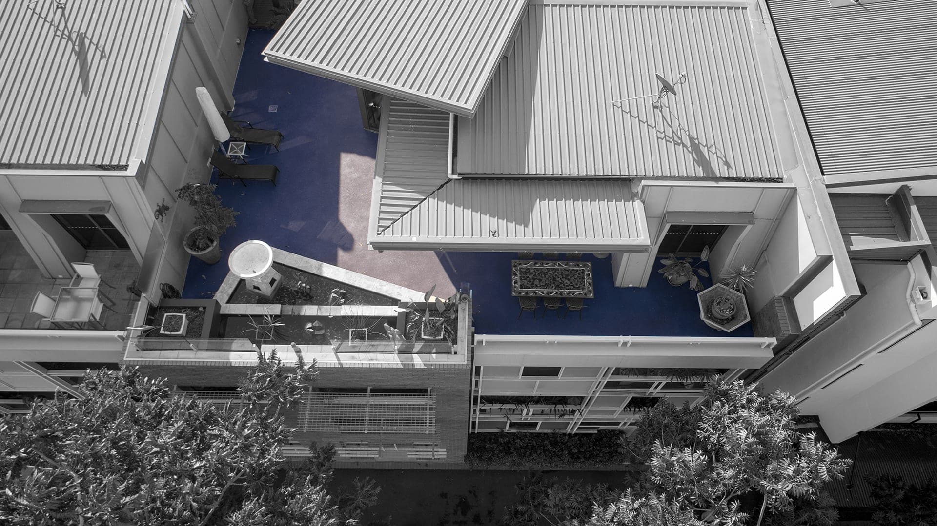 Drone view of a raised courtyard in Teneriffe finished in Grey-blue Covercrete, left in colour against a black and white edit of the rest of the photo.