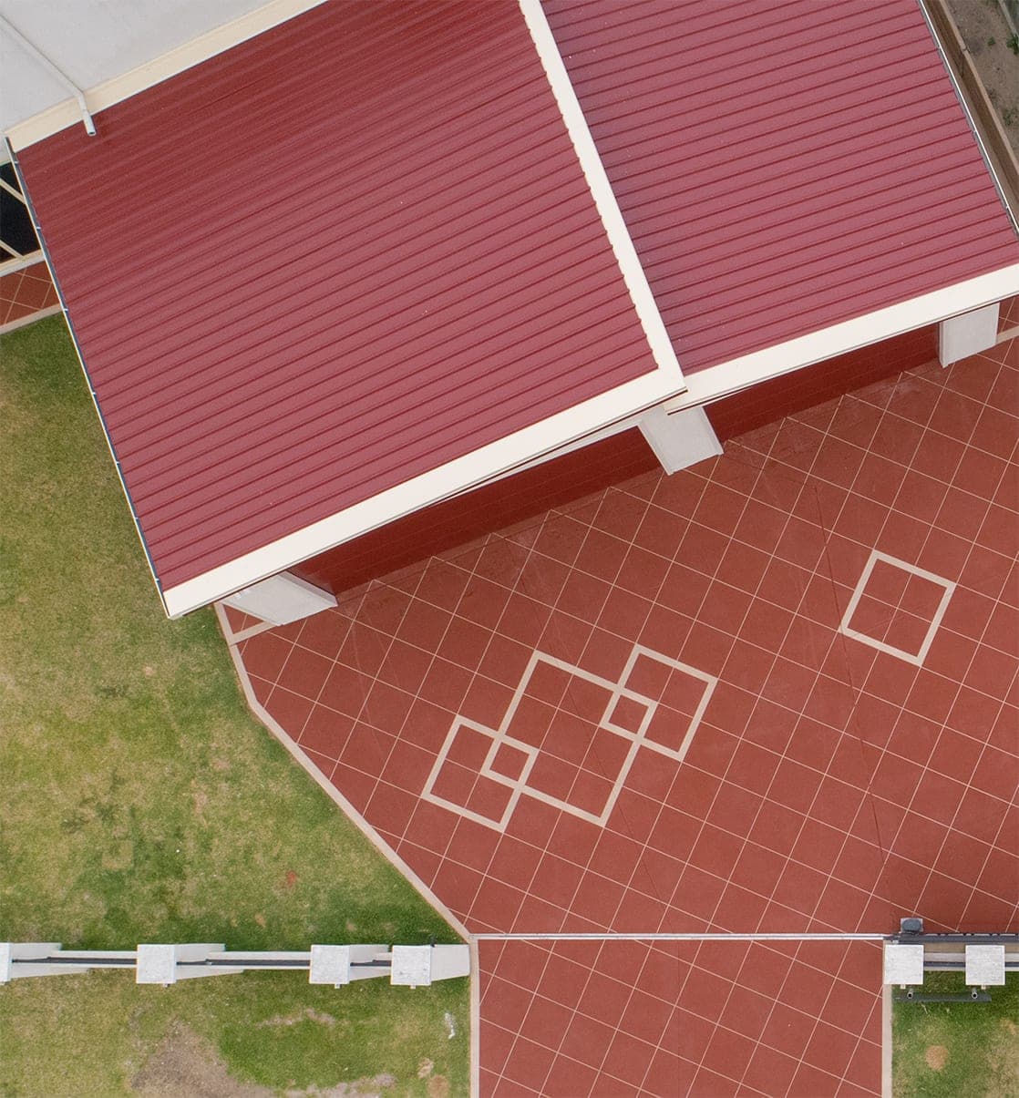 Overhead view of an Orange Brick Covercrete driveway in Stretton, with cream Stencil lines and a cluster of overlapping diamonds beside the garage roof.